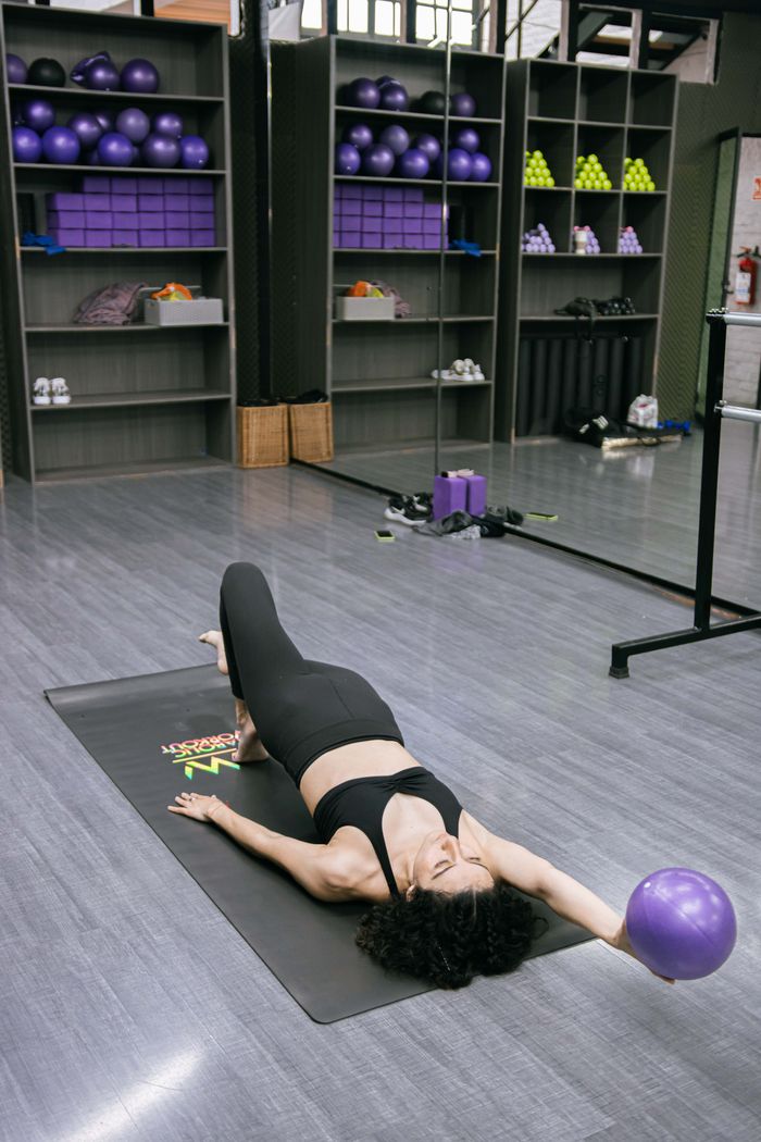 The Art of Drawing Readers In: Your attractive post title goes here A woman in sportswear exercising with a ball on a mat in a gym setting.
